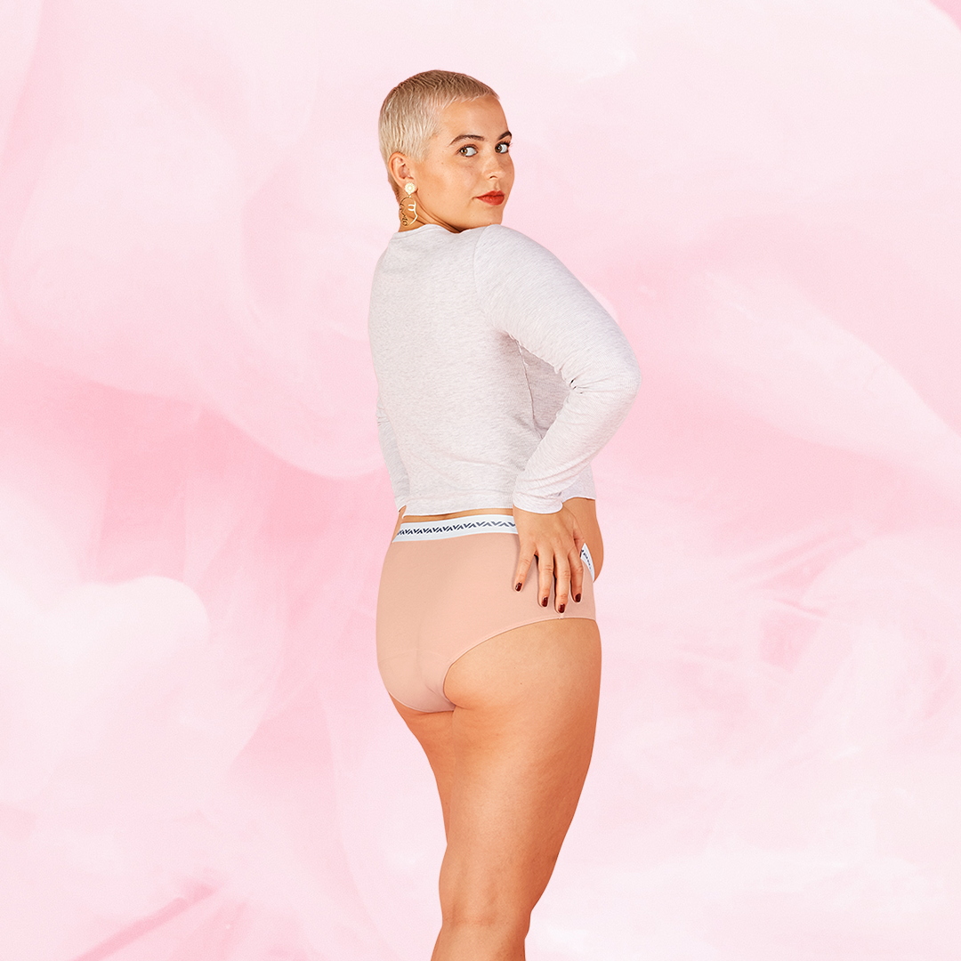 Woman in white shirt wearing ComfortFit Essentials Hipster Logo Waistband period pants, showcasing fit and coverage, highlighting innovative TriTech Performance technology for protection.